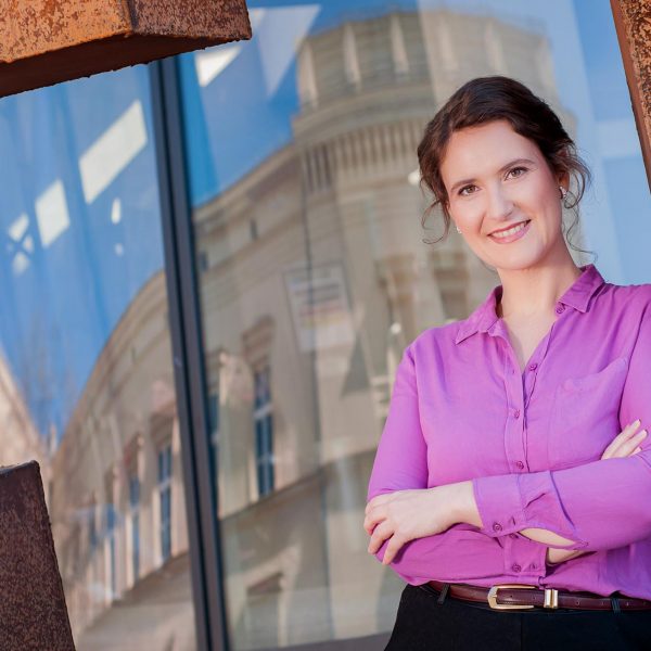 Portraitfoto einer Unternehmerin im Businessoutfit, stehend vor der Glasfassade des Deutschen Historischen Museums