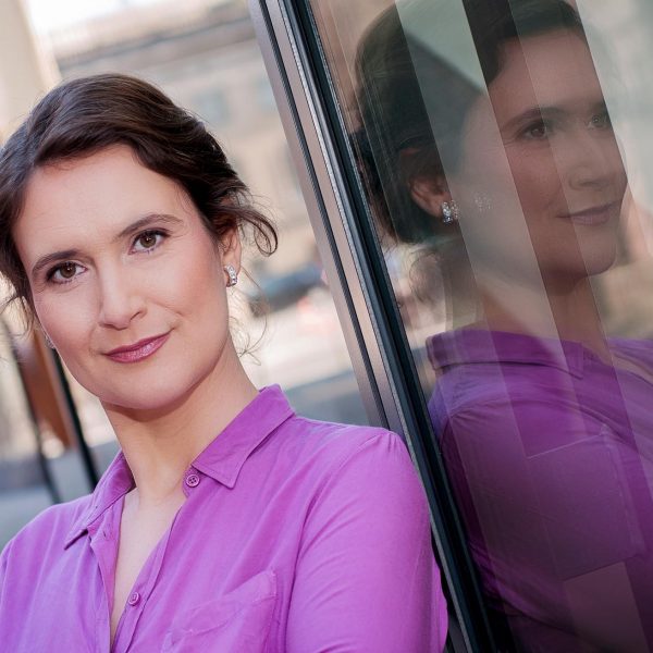 Portraitfoto einer Unternehmerin im Businessoutfit, stehend an der Glasfassade des Deutschen Historischen Museums
