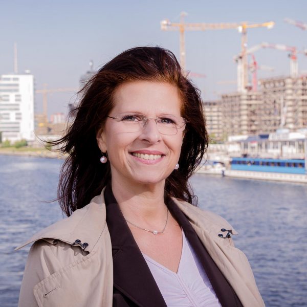 Portraitfoto einer Unternehmerin im Businessoutfit, stehend auf der Oberbaumbrücke mit der Spree im Hintergrund