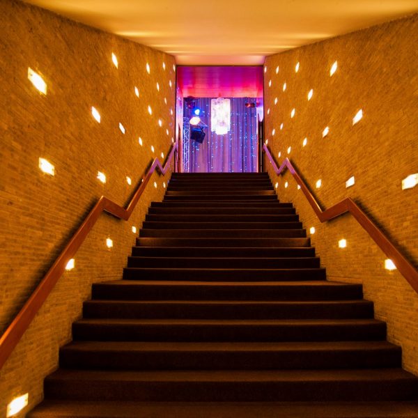Event- und Veranstaltungsfotos in Berlin - Interieurfoto eines Treppenaufgangs, an dessen Ende ein mit Effektlichtern beleuchteter Raum zu sehen ist