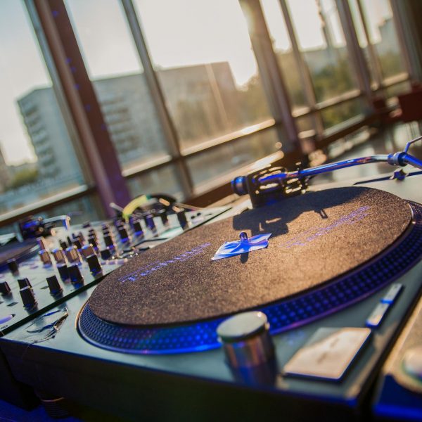 Event- und Veranstaltungsfotos in Berlin - Imagefoto eines Turntables von einem DJ Pult. Im Hintergrund sind durch die Panoramafenster des Raums schemenhaft die Silhouetten diverser Hochhäuser zu sehen