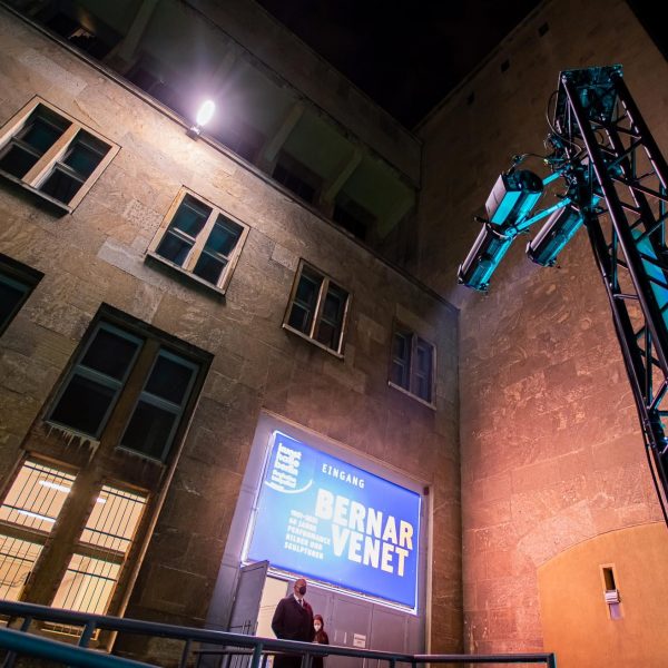 Event- und Veranstaltungsfotos in Berlin - Außenaufnahme des Eingangsbereichs eines Hangars vom Tempelhofer Flughafen, vor dem eine Traverse mit Effektlichtern aufgebaut ist, die auf das Gebäude gerichtet sind