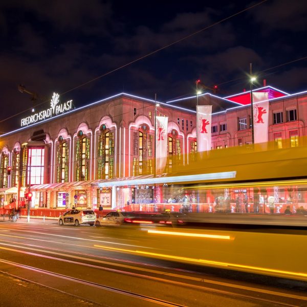 Event- und Veranstaltungsfotos in Berlin - Außenaufnahme des bei Nacht beleuchteten Friedrichstadt Palast, mit einer davor vorbei fahrenden Straßenbahn