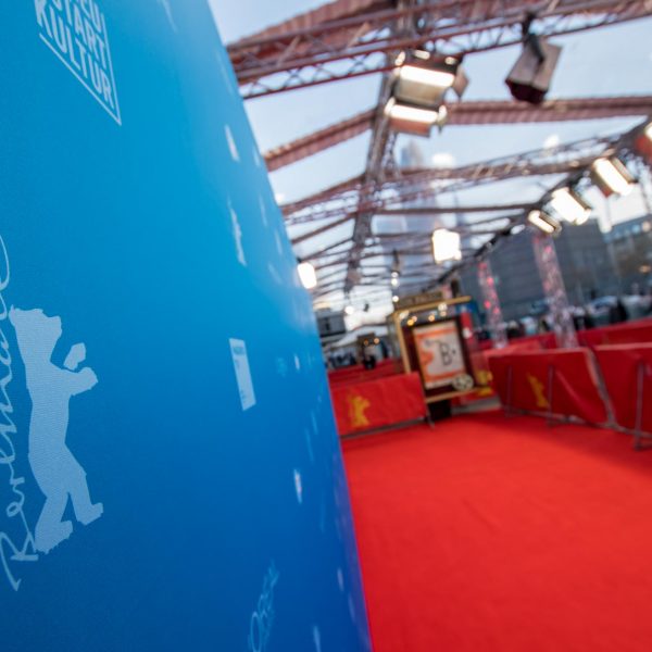 Event- und Veranstaltungsfotos in Berlin - Imagefoto einer Fotowand, auf der das Logo der Berlinale im Vordergrund zu sehen ist. Im Hintergrund ist eine mit diversen Lampen behangene Konstruktion, sowie ein roter Teppich zu sehen
