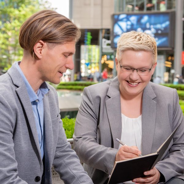 Corporate Fotografie in Berlin - Imagefoto eines Beratungsgesprächs zweier Geschäftsleute auf einer Bank im Sony Center sitzend