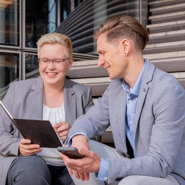 Corporate Fotografie in Berlin - Imagefoto eines Beratungsgesprächs zweier Geschäftsleute auf einer Treppe am Potsdamer Platz sitzend
